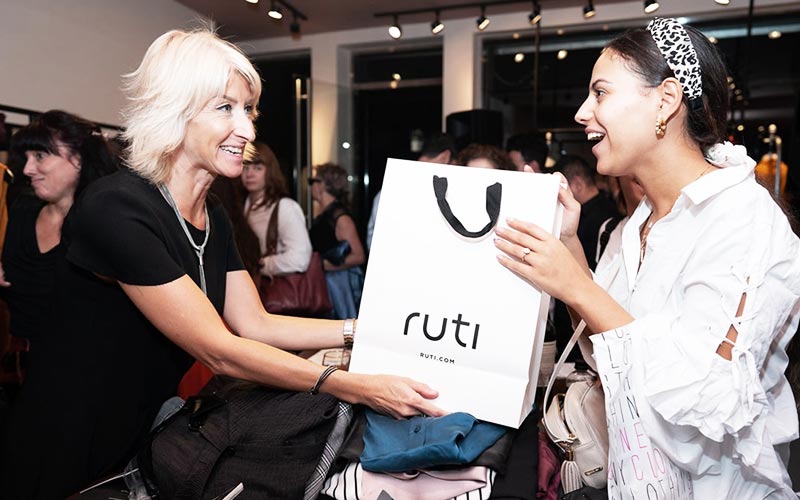 woman handing another woman a gift bag from a retail store