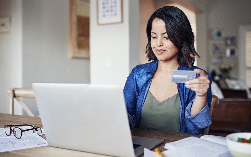 Frau bezahlt mit Kreditkarte am Macbook