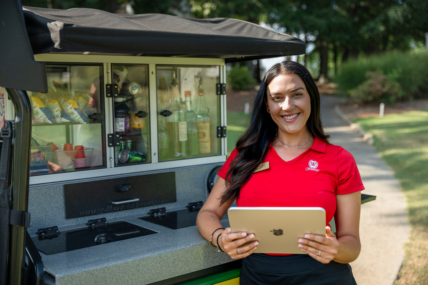 a golf course employee serves food and drinks from a golf cart on a course. Golf culture is changing and it requires golf courses to adapt to new technology.