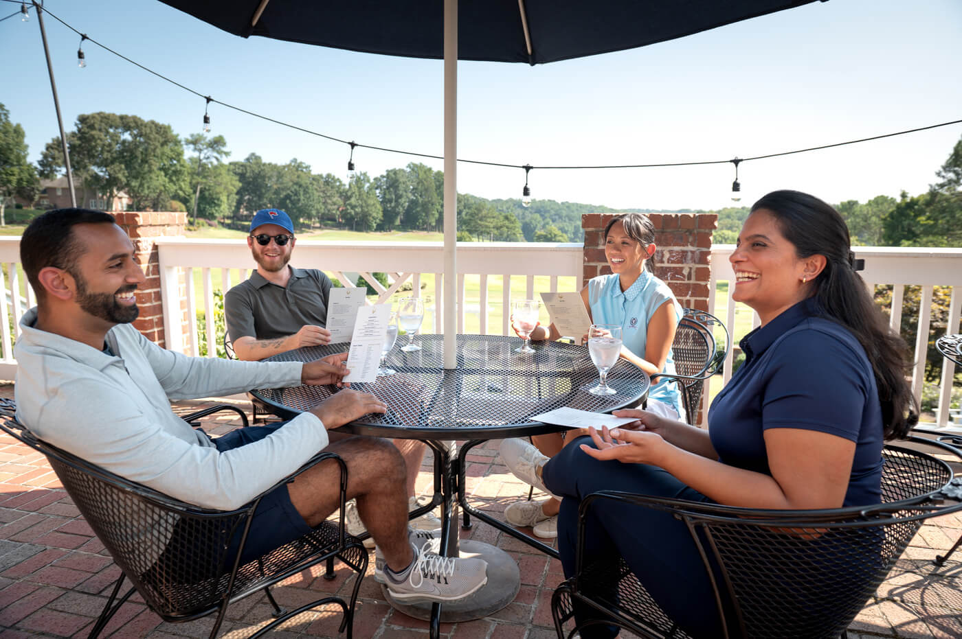 golfers gather to eat and drink on a golf course patio. golf culture is all about delivering an amazing, welcoming customer experience.