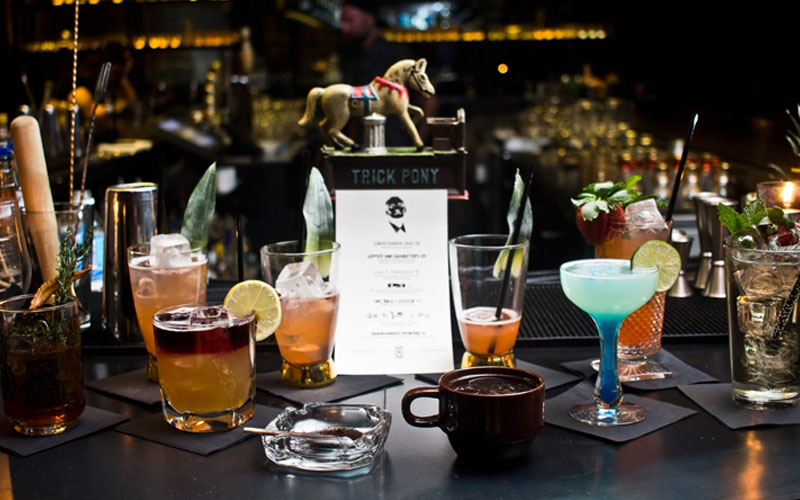 A bar top displaying a variety of colorful cocktails