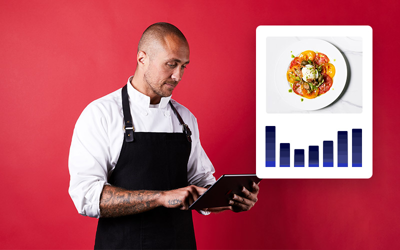 A man in a white shirt and black apron looks down at an iPad. To the left is an illustration of a bar graph under a photo of a tomato salad.