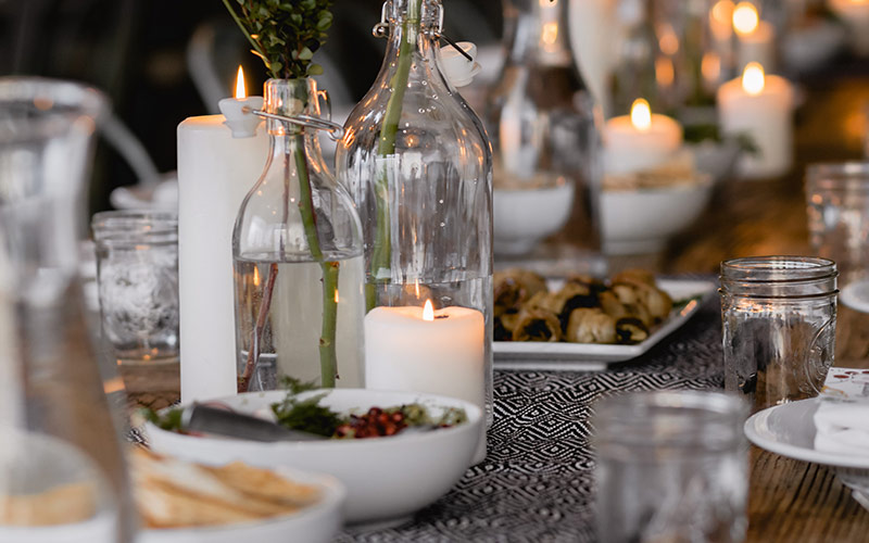 Close up of a table setting with candles and flower vases.