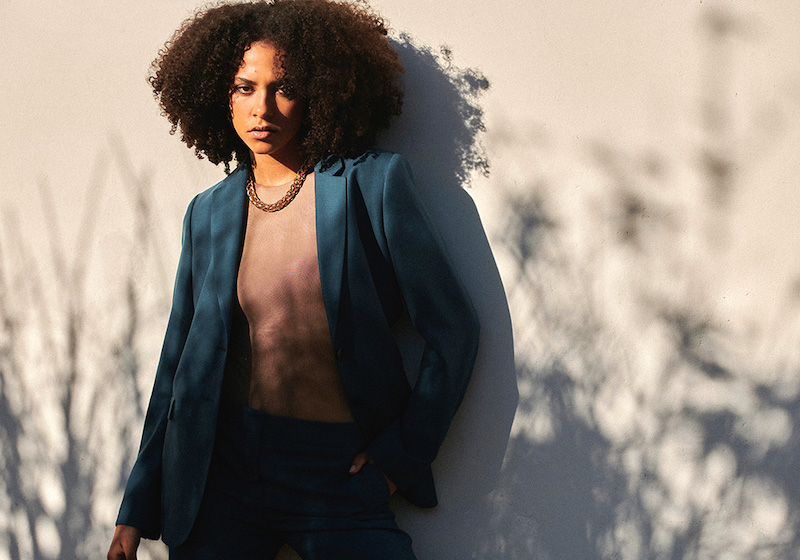 vrouw met groen pak leunt tegen muur