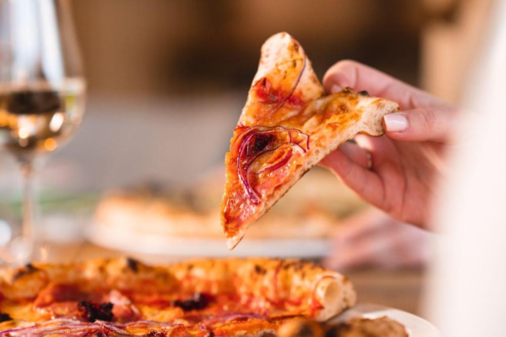 Stuk Pizzza in de hand