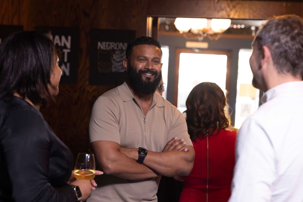Dax Dasilva, CEO & Founder of Lightspeed, with crossed arms smiles during a casual conversation at an industry event.