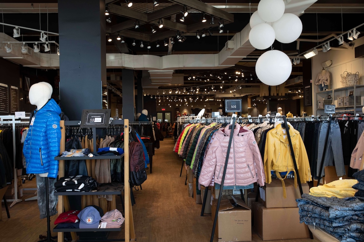 The interior of a store showing racks of winter coats, mannequins and jeans.
